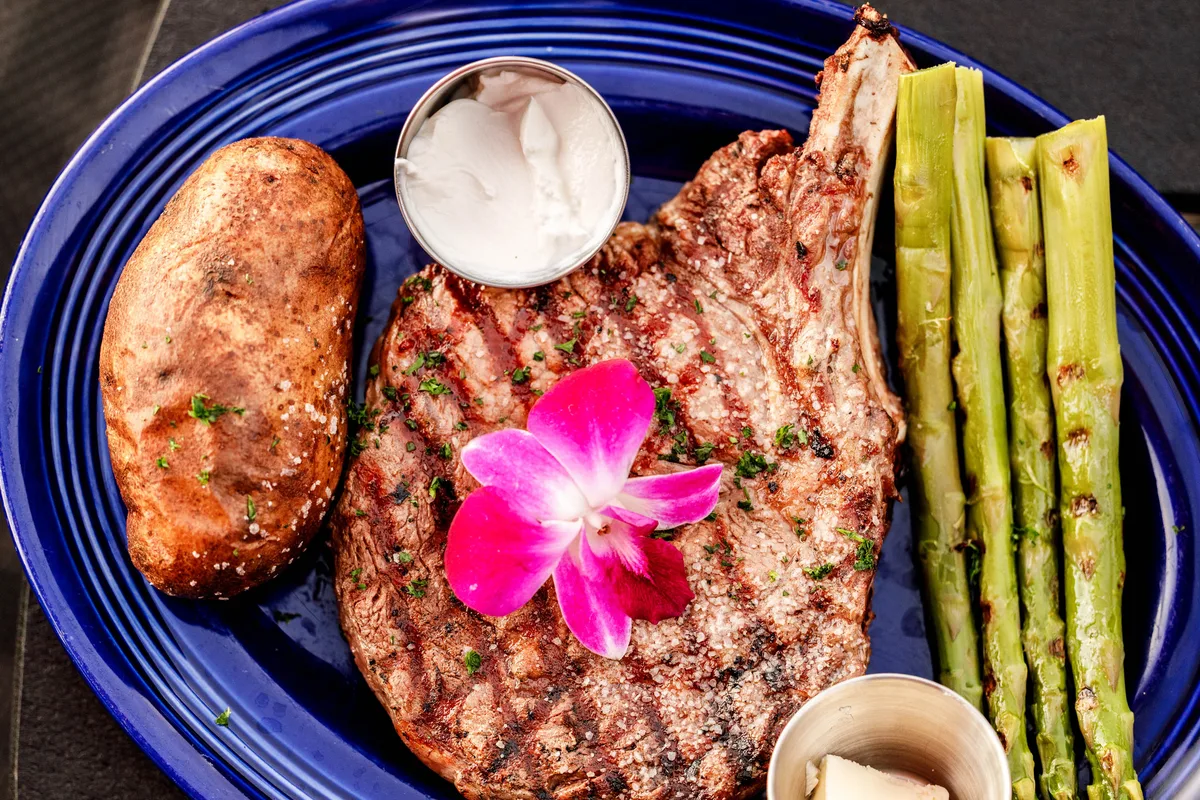 Grilled steak with baked potato and asparagus on a blue plate